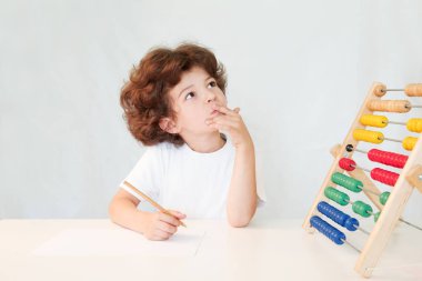 El ve puanları düşünceli arıyorum masanın üzerine bir kurşun kalemle sevimli kıvırcık saçlı çocuk. Yakın çekim. Gri arka planı.