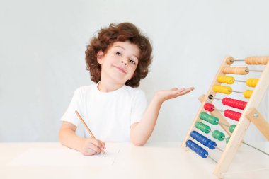 Elinde puanları gösteren bir kalem ile sevimli kıvırcık saçlı çocuk. Yakın çekim. Gri arka planı.