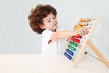 Küçük kıvırcık çocuk saymak öğrenme. Yakın çekim. Gri arka planı.