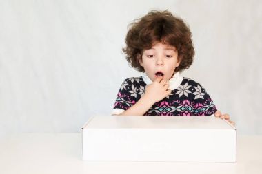 Düşünceli genç yakışıklı bir süsleme ağzı açık, kazak beyaz kutu bakar. Gri arka planı.