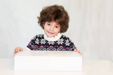 Kazaklı bir süsleme ile mutlu sevimli çocuk kameraya bakıyor. Beyaz kutu elele. Gri arka planı.