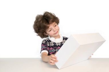 Beyaz kutu tutarak ve ona bakmak hoş küçük çocuk memnun. Beyaz arka plan.