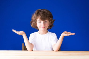 Kıvırcık sevimli çocuk kollarını, avuç içi kadar yayıldı. Yakın çekim. Mavi arka plan.