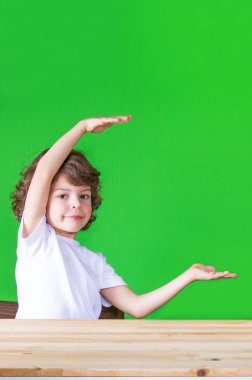 Büyük gösterilen kıvırcık sevimli çocuk hayali nesne, gülümseyen ve kameraya bakarak eller. Yakın çekim. Yeşil arka plan.