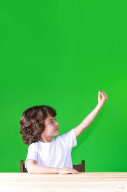 Bir masada oturan kıvırcık yakışıklı yarı-elini kaldırdı döndü. Yakın çekim. Yeşil arka plan.