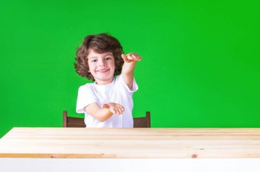 Eller hayali nesne tutan, gülen ve kamera seyir kıvırcık sevimli çocuk. Yakın çekim. Yeşil arka plan.