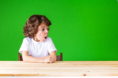 Kıvırcık yakışıklı ağzını açın sola bakıyor. Yakın çekim. Yeşil arka plan.