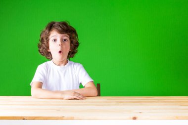 Kıvırcık yakışıklı ağzını açın kameraya bakıyor. Yakın çekim. Yeşil arka plan.