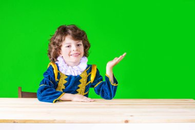 Prens giysili bir el, palmiye up, kameraya doğru seyir gidiyor mutlu kıvırcık saçlı çocuk. Yakın çekim. Yeşil arka plan.