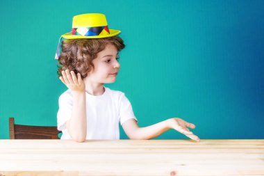 Ellerini yukarı sola arıyorsunuz avuç içi kadar çocuğu kıvırcık sarı hat palyaço attı. Yakın çekim. Mavi arka plan.