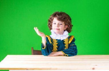 Masada oturan sevimli küçük prens sağ elinde, palm yukarı kaldırdı. Yakın çekim. Yeşil arka plan.