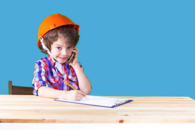 Bir cep telefonu tutan, gülüyor, kameraya bakarak bir defter kalem yazma genç kıvırcık baş komiser. Yakın çekim. Mavi arka plan.