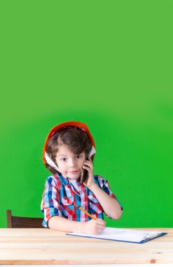 Gülümseyen, kameraya bakarak bir defter kalem yazma bir telefon tutarak genç yakışıklı foreman. Yakın çekim. Yeşil arka plan.