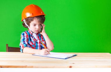 Ciddi küçük Foreman'ın elinde bir telefon ile bir defter kalem yazdı. Yakın çekim. Yeşil arka plan.