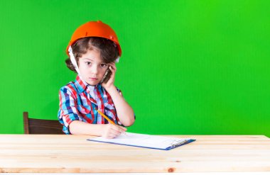 Kameraya bakarak bir defter kalem yazma kask içinde genç yakışıklı foreman. Yakın çekim. Yeşil arka plan.