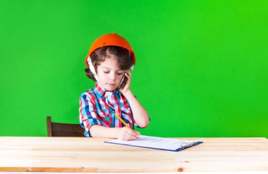 Genç yakışıklı foreman bir defter kalem yazma kask içinde. Yakın çekim. Yeşil arka plan.