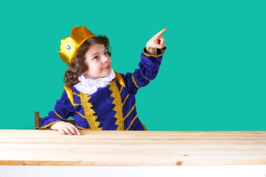 Küçük kıvırcık Prens ararken işaret parmağı ile işaret eder. Yakın çekim. Turkuaz arka plan.