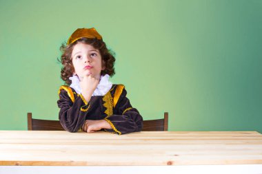 Genç kıvırcık üzgün Prens dikkatle baktı. Yakın çekim. Yeşil arka plan.