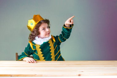 Genç kıvırcık Prens onun parmağı işaret eder. Yakın çekim. Yeşil arka plan.