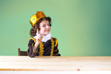 Genç yakışıklı prens kameraya bakarak işaret parmağı tehdit ediyor. Yakın çekim. Yeşil arka plan.