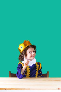 Genç yakışıklı prens bir işaret parmağı yüzler gülümsüyor, kameraya bakıyor. Yakın çekim. Turkuaz arka plan.