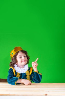 Genç yakışıklı prens kameraya bakarak, işaret parmağı ile işaret. Yakın çekim. Yeşil arka plan.