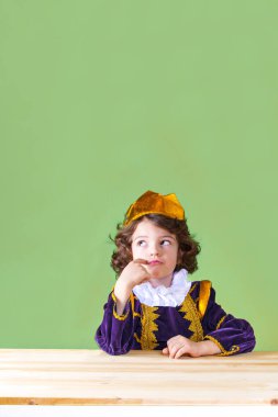 Düşünceli kadar seyir masada oturan genç kıvırcık Prens. Yakın çekim. Yeşil arka plan.