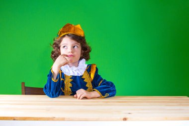 Düşünceli kadar seyir masada oturan üzgün kıvırcık Prens. Yakın çekim. Yeşil arka plan.