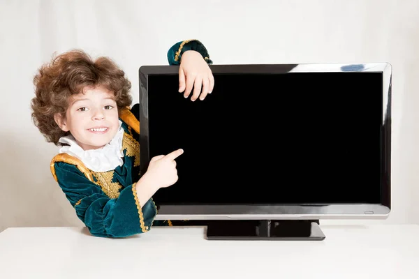 Söt kinky prince allomfattande TV, pekar han sitt pekfinger på en tom skärm. Grå bakgrund. — Stockfoto