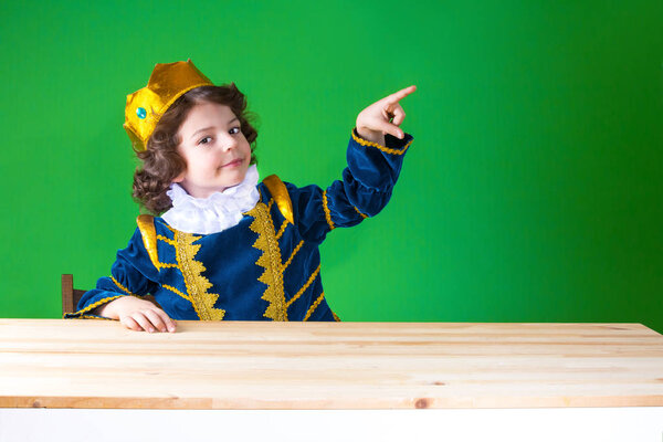 Young curly Prince indicates the index finger and looking at the camera. Close-up. Green background.