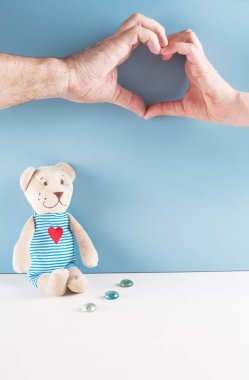 Bir mavi arka plan teddy ayı oturur. Onu erkek ve dişi eller 