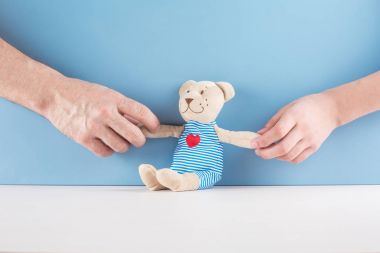 Erkek ve dişi bir oyuncak ayı bacaklar için holding eller. Mavi arka plan.