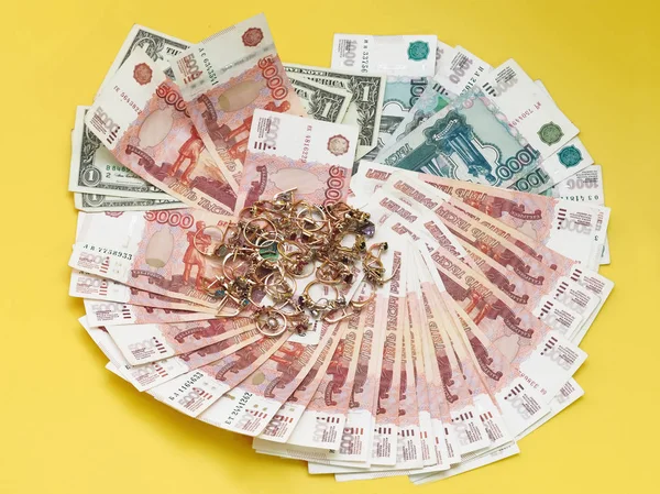 Altın yüzük ve küpeler Lirası üstünde vardır. Sarı arka plan.