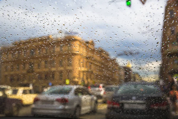 Paesaggio urbano attraverso gocce di pioggia sul vetro . — Foto Stock