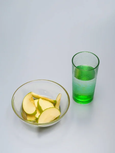 In Scheiben geschnittener grüner Apfel liegt in einem Teller, der mit Honig bedeckt ist. In der Nähe steht ein Glas Wasser. — Stockfoto