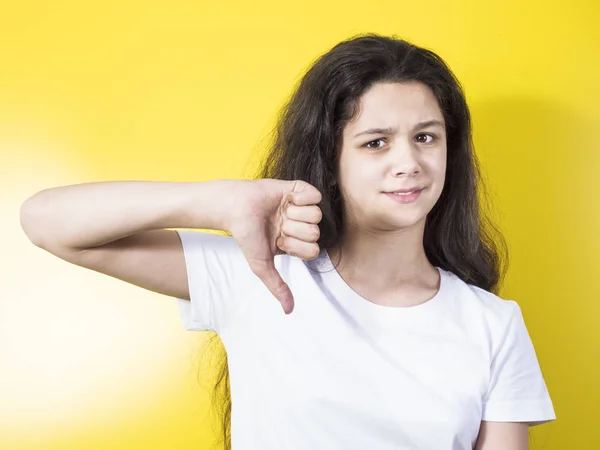 Jonge vrouw met een duim omlaag gebaar. Gele achtergrond — Stockfoto