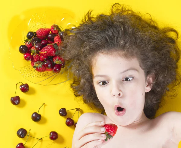 Fiú izgatott, hogy enni az epret. Sötét haja, Pigtailek. Eper, meggy, érett, vörös. — Stock Fotó