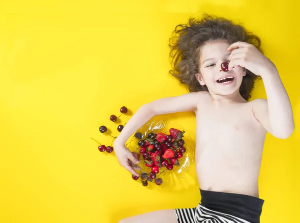 Cute chłopiec dziecko jedzenie zdrowej ekologicznej żywności, świeżych owoców. Żółte tło z miejsca na tekst lub obraz. — Zdjęcie stockowe