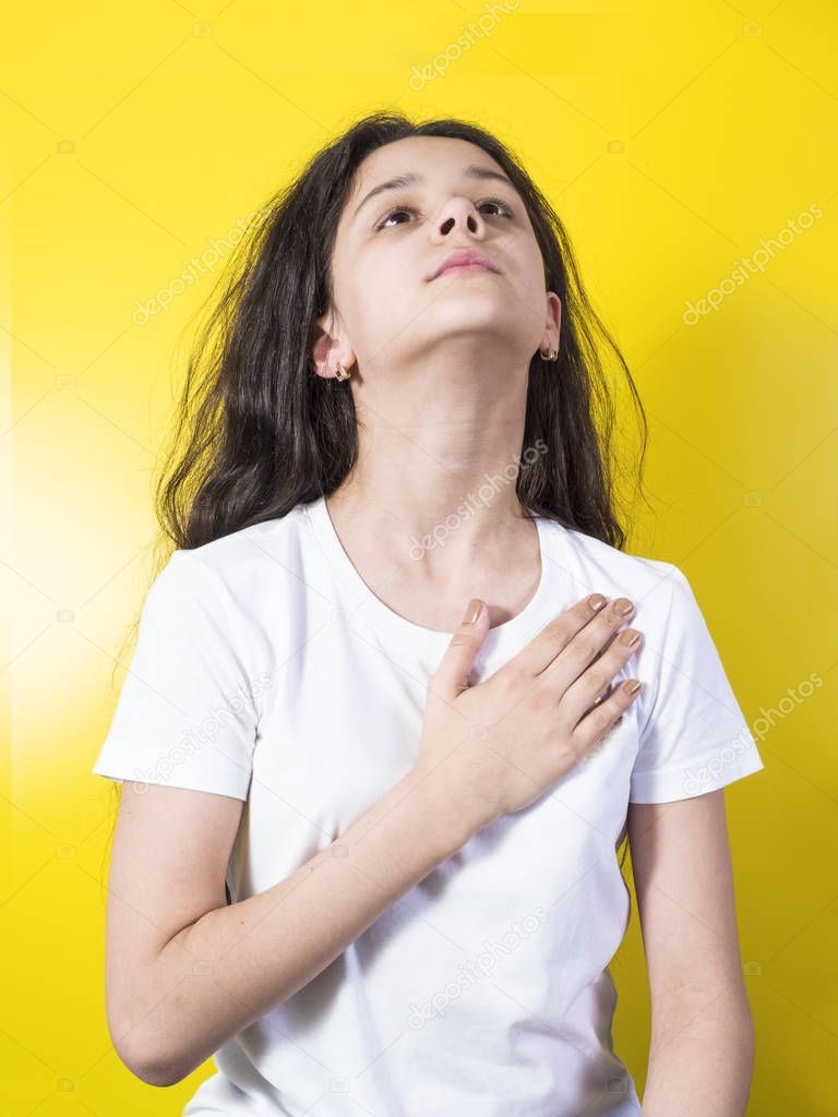 Young woman swears or promises. Yellow background