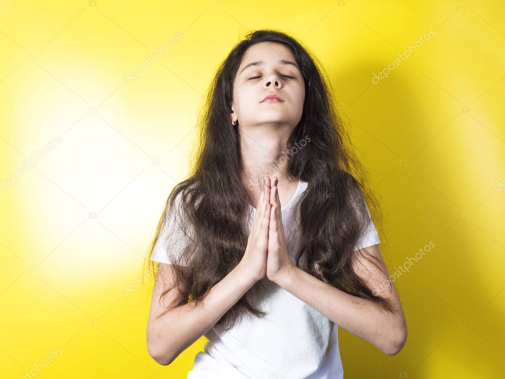 An attractive girl in a white T-shirt folded her arms and asked for something. Yellow background