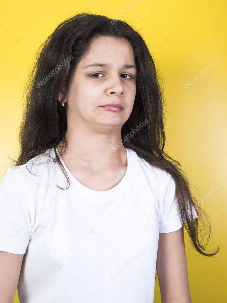 Girl disgusted face expression. Yellow background.