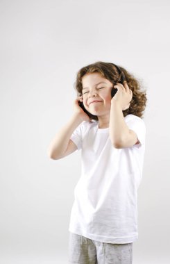 Müzik ve teknoloji kavramı. Kulaklık gri arka plan üzerinde beyaz küçük çocuk