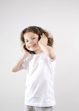 Müzik ve teknoloji kavramı. Kulaklık gri arka plan üzerinde beyaz küçük çocuk