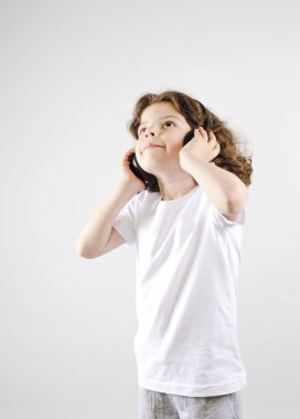 Müzik ve teknoloji kavramı. Kulaklık gri arka plan üzerinde beyaz küçük çocuk