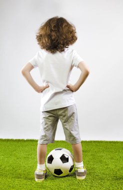 Gençlik futbol oyuncusu ayakta taraf yeşil çimenlerin üzerinde ellerini tutarak. Arkadan görünüş