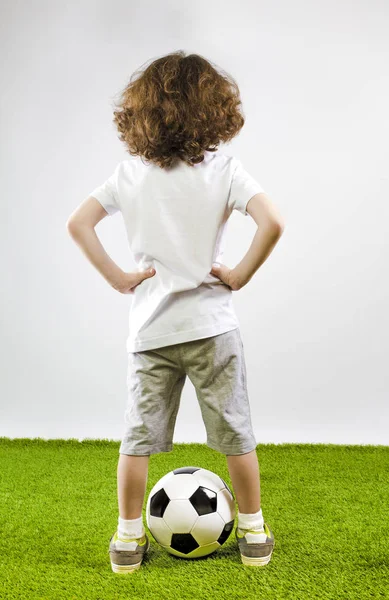 Gençlik futbol oyuncusu ayakta taraf yeşil çimenlerin üzerinde ellerini tutarak. Arkadan görünüş