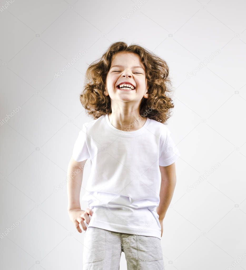 Surprised boy laughing out loud on a gray background.