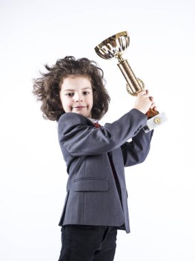 Sevimli küçük kıvırcık çocuk ayakta ve bir fincan tutan bir takım elbise. Gri arka planı