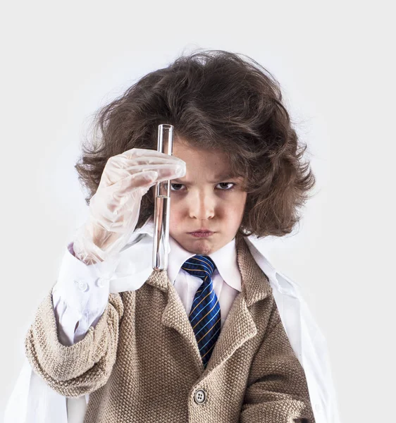 Küçük kıvırcık saçlı çocuk bilim adamı tüp berrak sıvı ile görünüyor. Gri arka planı