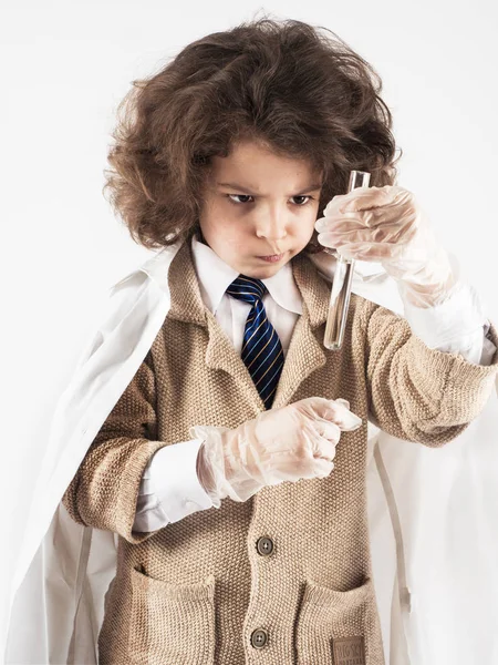 Akıllı küçük kıvırcık saçlı çocuk bilim adamı tüp berrak sıvı ile görünüyor. Gri arka planı